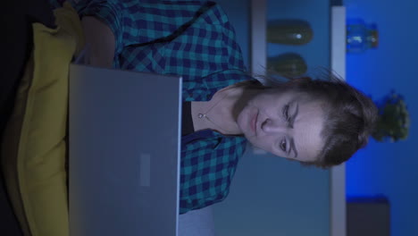 Vertical-video-of-Woman-focusing-on-computer-has-serious-expression.-At-home-at-night.